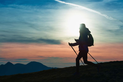 Low angle view of silhouette man standing on mountain against sky during sunset