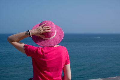 Rear view of woman wearing hat against sea and sky