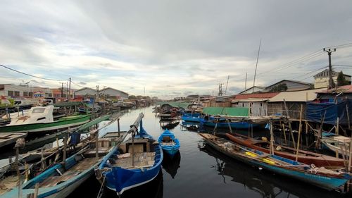 Boats moored at harbor against sky