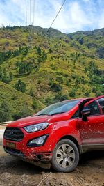 Red car on land against sky