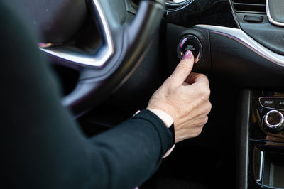 Woman starts the car engine with start-stop button. modern car interior, closeup