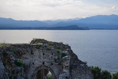 Castle by sea against cloudy sky