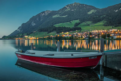 Boats moored on lake against mountains