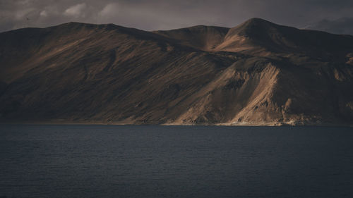 Scenic view of mountain by sea against sky