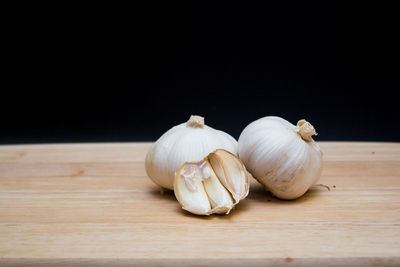 Close-up of garlic on table against black background
