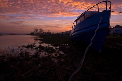 Sailboats moored on sea against sky during sunset