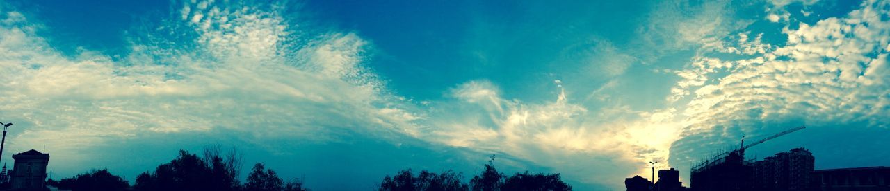 sky, low angle view, cloud - sky, blue, building exterior, silhouette, built structure, architecture, cloud, tree, cloudy, beauty in nature, nature, scenics, city, outdoors, no people, high section, tranquility, building