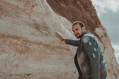 Smiling man standing by rock formation