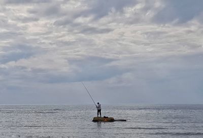 Fishing rod on sea against sky