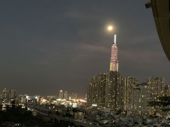 Illuminated modern buildings in city against sky at night