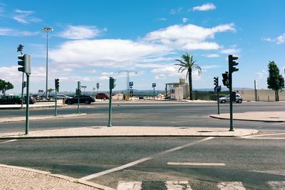 Cars moving on street against cloudy sky