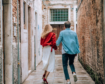 Rear view of couple walking on building