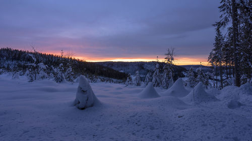 Scenic view of snow covered field against sky during sunset