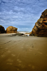 Rock formations on beach against sky