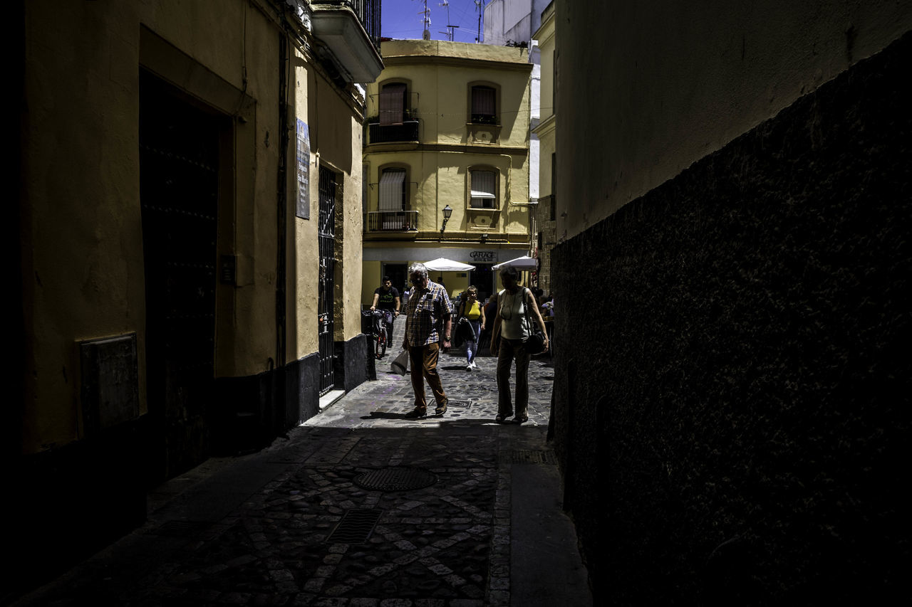 architecture, built structure, building exterior, group of people, walking, men, real people, lifestyles, the way forward, building, people, direction, leisure activity, full length, women, city, day, rear view, outdoors, street, alley