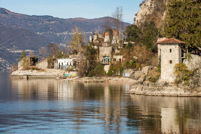 Old ruined furnaces with chimneys with red bricks reflecting on the water of lake maggiore 