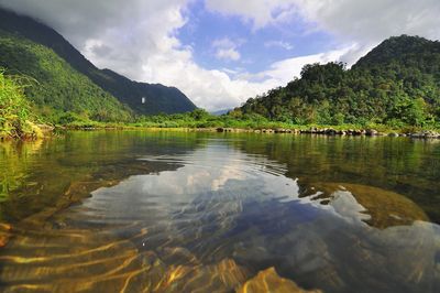 Scenic view of lake by mountains against sky