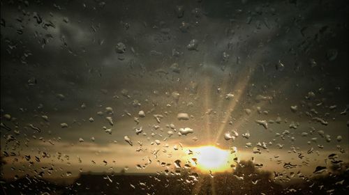 Close-up of waterdrops on glass against sunset