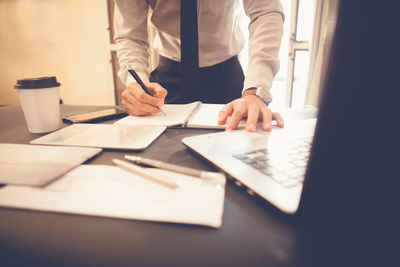 Midsection of man using mobile phone on table