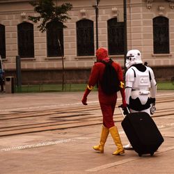 Rear view of people in costume walking on footpath