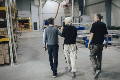 Full length of businessman discussing with colleagues while walking in industry