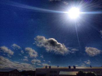 Low angle view of sun shining through clouds