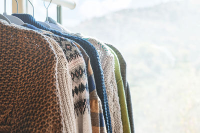 Knitted sweaters on hangers on the clothes rack. slow fashion. conscious consumption. garage sale