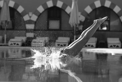 Reflection of woman in swimming pool against building