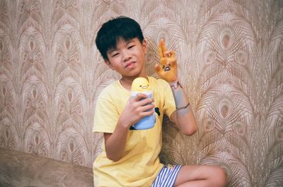 Full length of boy holding toy against wall