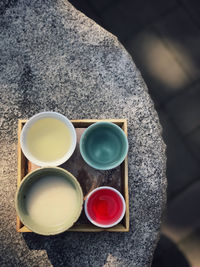 Colourful rice wine on a tray on a rock with light and shadow