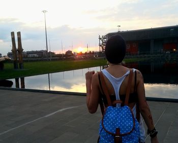 Rear view of man standing on riverbank against sky