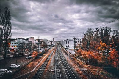 Train on railroad tracks in city against storm clouds