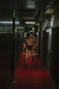 Rear view of man standing in illuminated building