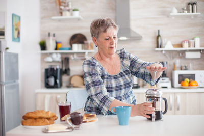 Senior woman making coffee at home