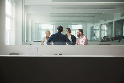 Business people discussing in office seen through window