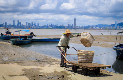 Man working on boat in sea against sky