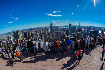 Group of people in city against blue sky