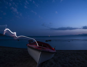 Boat moored on beach against sky