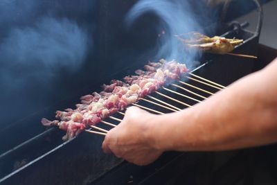 Close-up of person preparing food on barbecue grill