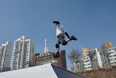 Low angle view of man jumping against clear sky