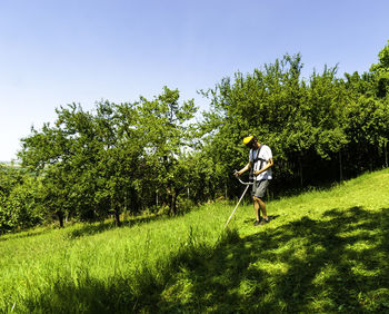 Full length of man cutting grass with weed trimmer