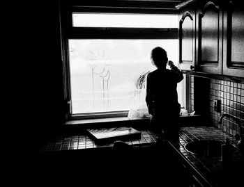 Rear view of boy standing in window
