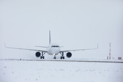 Traffic at airport during snowfall. passenger airplane taxiing to runway for take off on winter day.