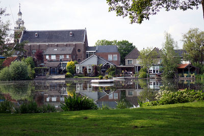 Houses by lake and buildings against sky