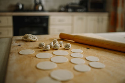 Rolling pin by dumplings on cutting board in kitchen at home
