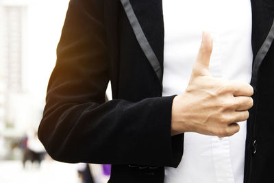 Midsection of businesswoman gesturing while standing outdoors