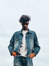 Young man in sunglasses standing against sky