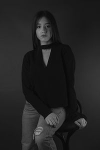 Portrait of young woman against black background