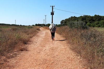 Rear view of man walking on dirt road