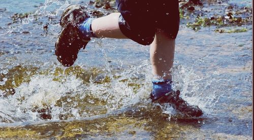 Low section of boy standing in sea